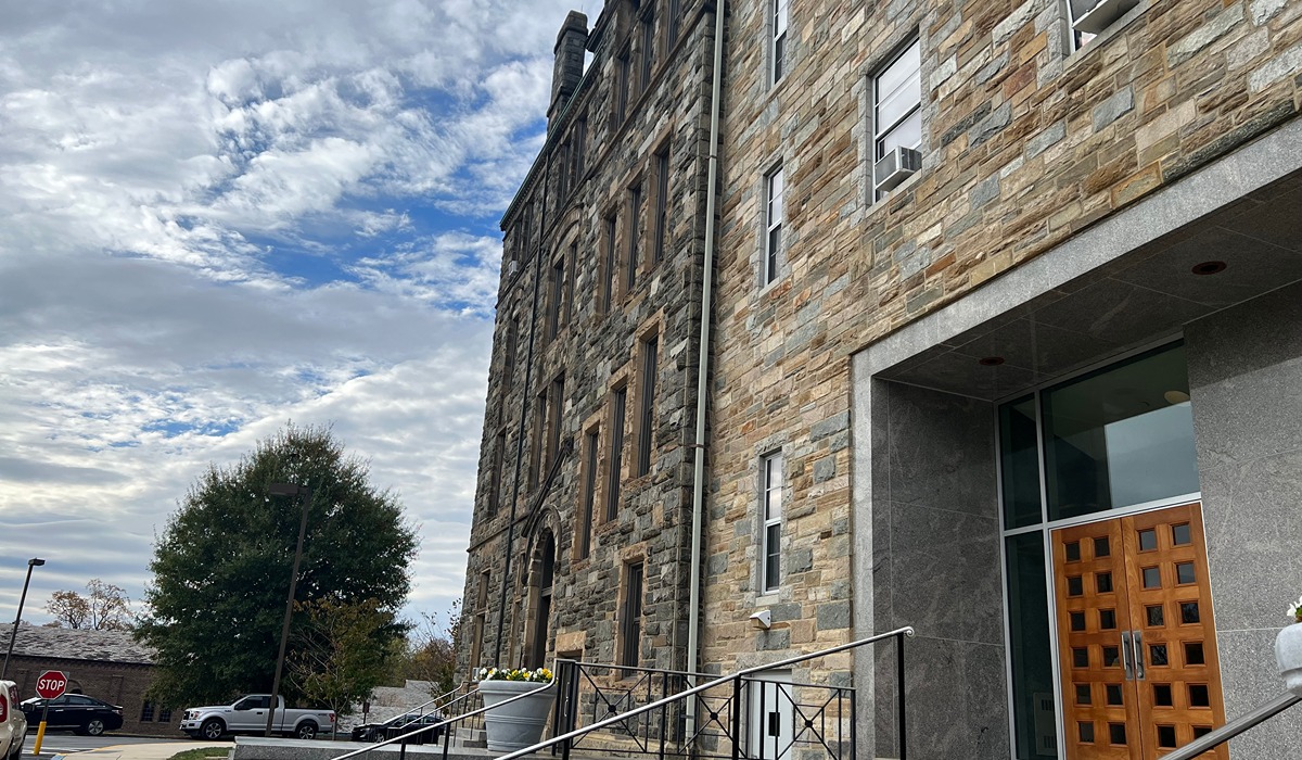 Cladwell Hall, a stone building, stands tall agains the blue sky.