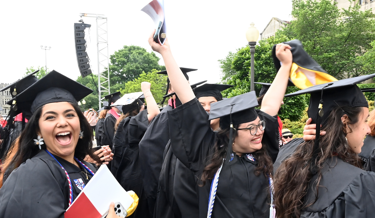 Graduates celebrating their achievement outside smiling