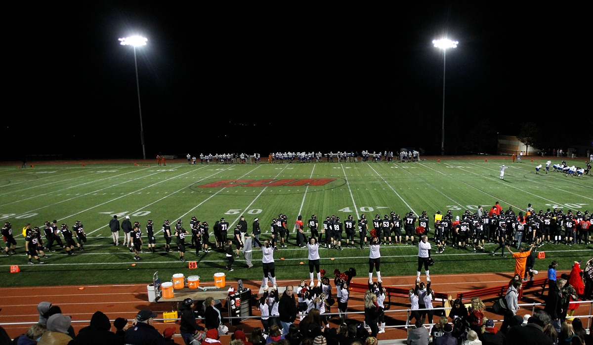 football field from bleachers perspective players are lined up on the sidelines