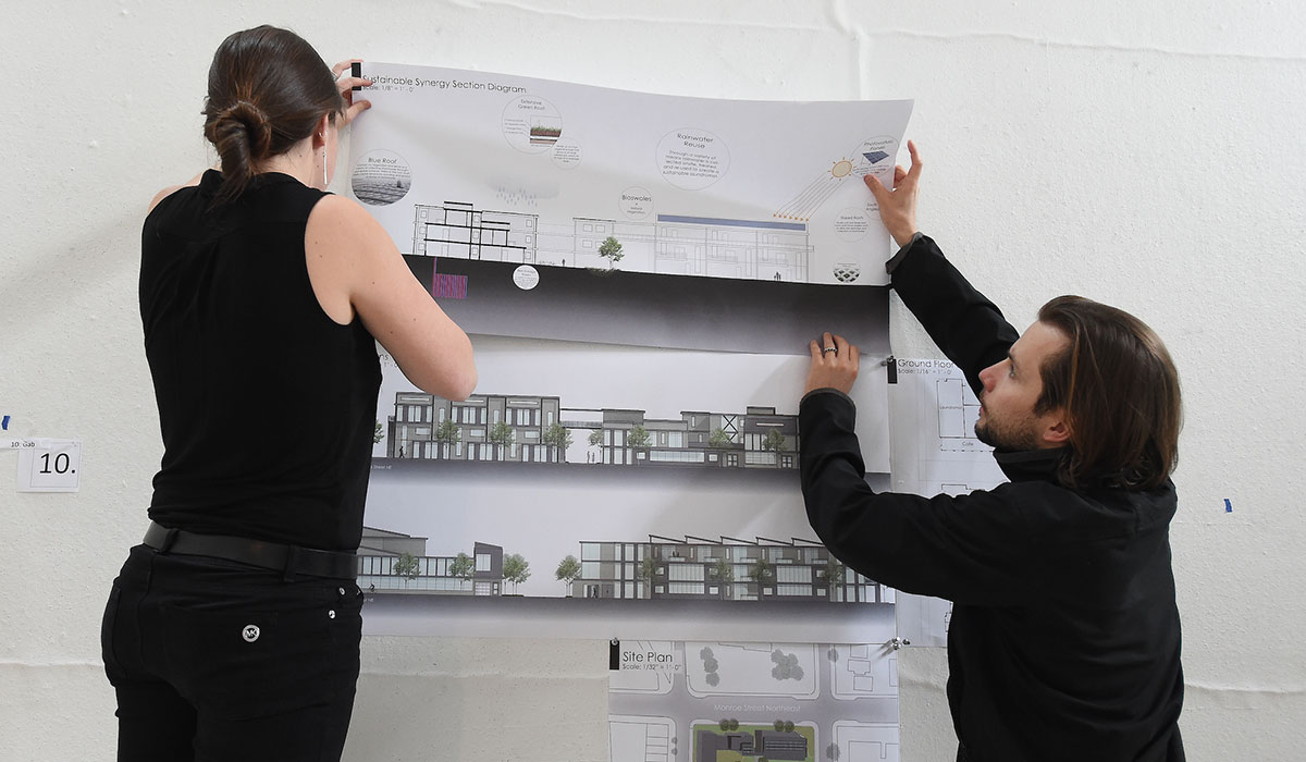 Two students holding up drawings