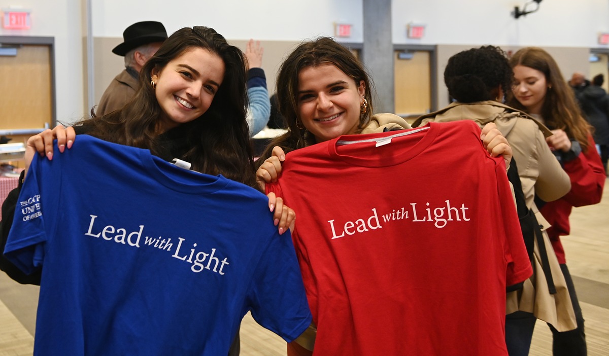 Two students posing with "lead with light" shirts