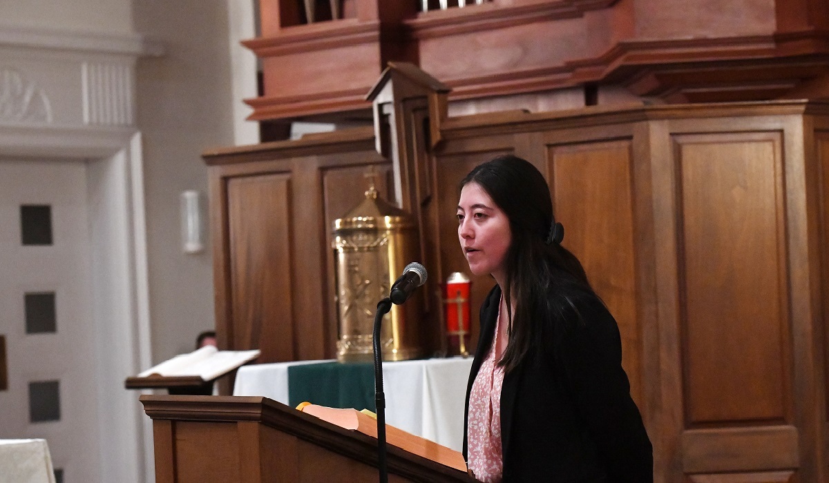 Student Government President Maevis Fahey speaking at a podium