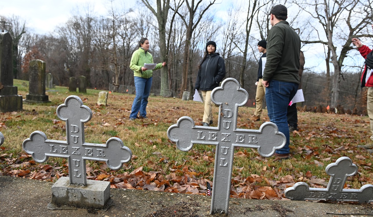 Laura Masur, an assistant professor of anthropology, takes University students to Sacred Heart Chapel in Bowie, Md., to clear brush at the parish’s cemetery, which is the final resting place for enslaved, free and White persons.  The students marked potential gravesites with flags for further research. 