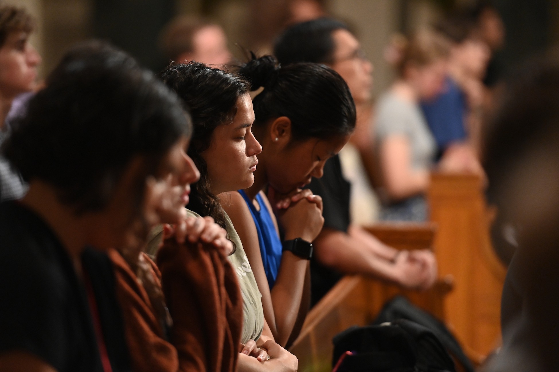 student with eyes closed praying at mass