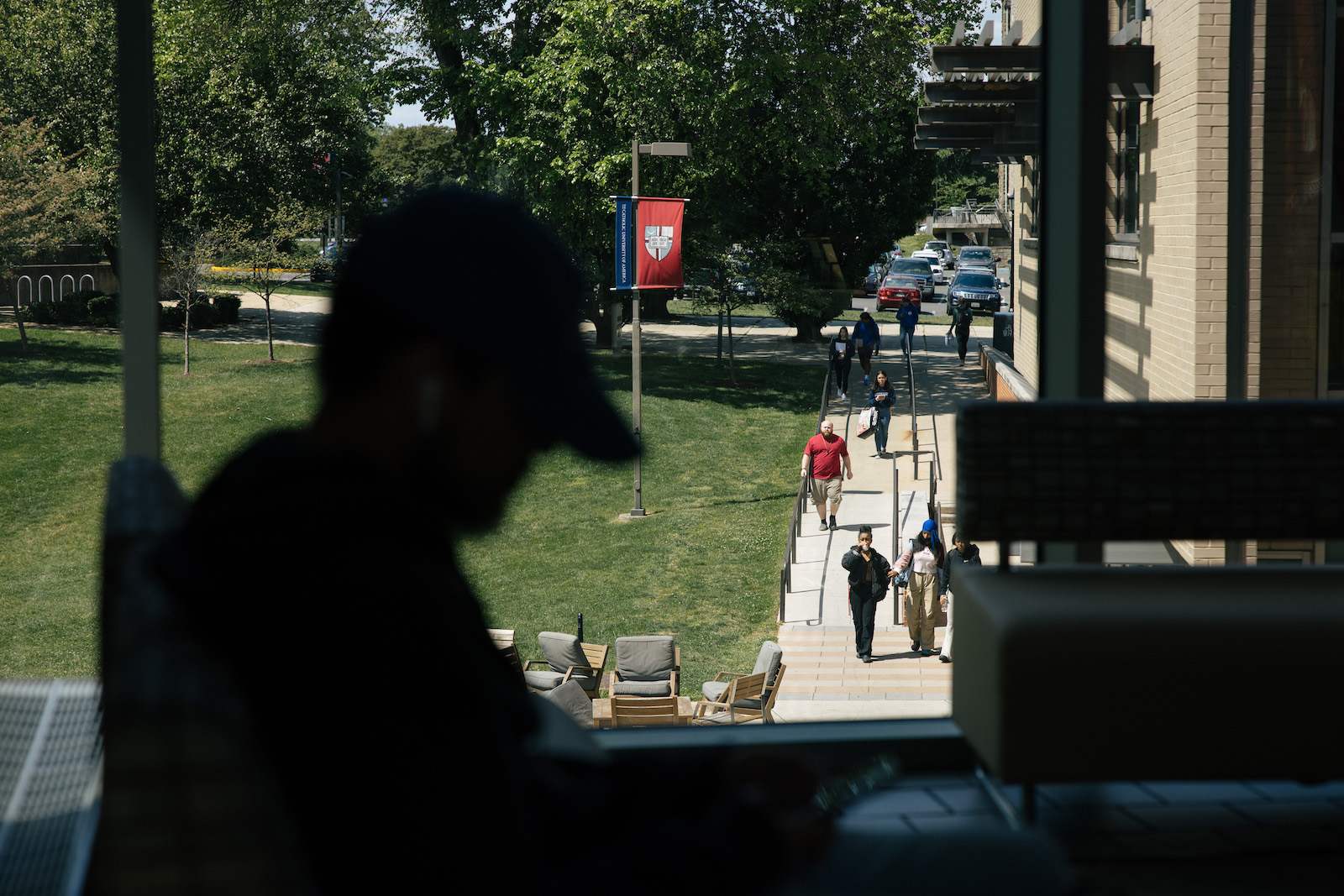 student's sillhouette as he works with a bustling campus in the background