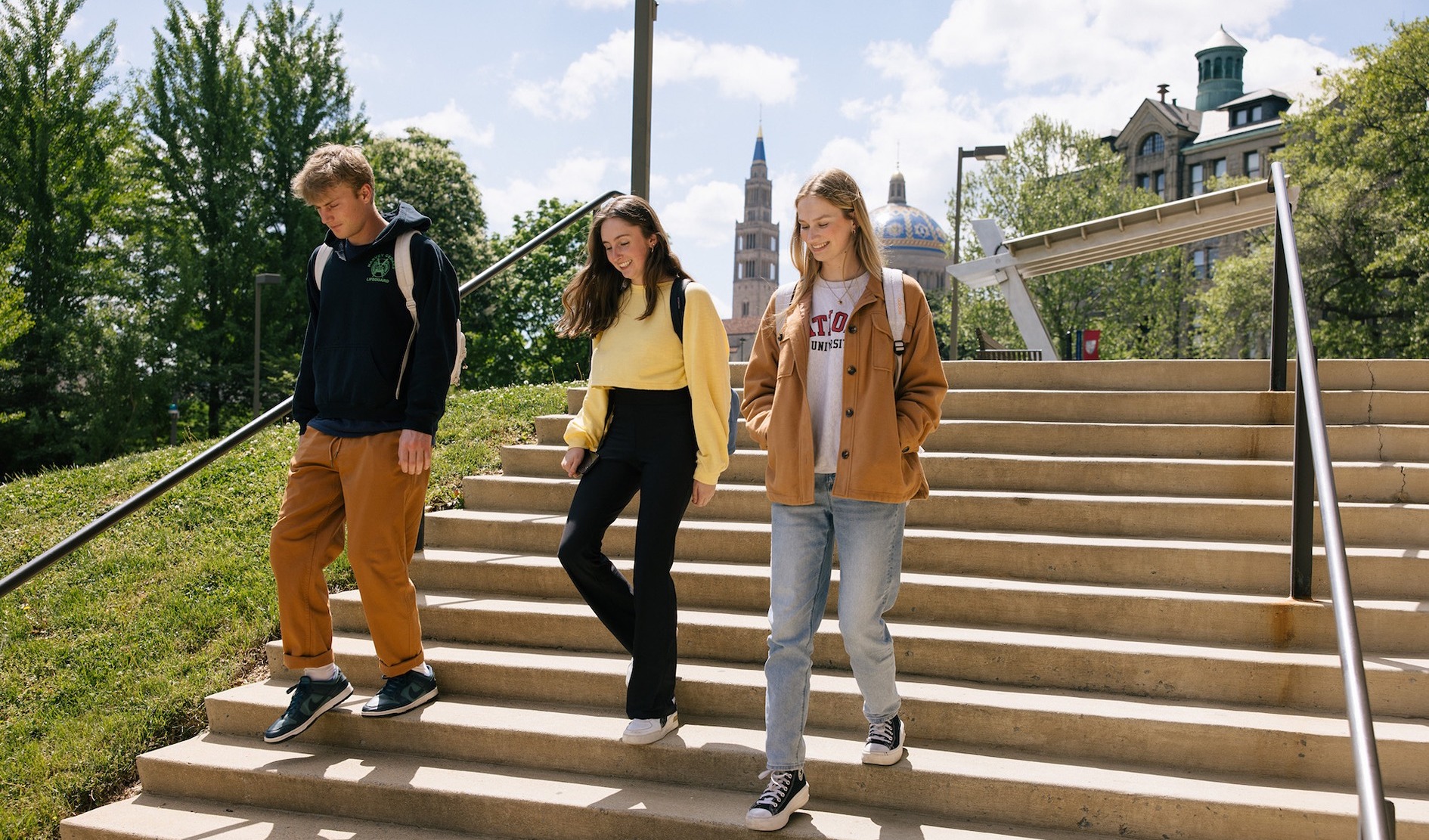 students walking down steps on campus and smiling