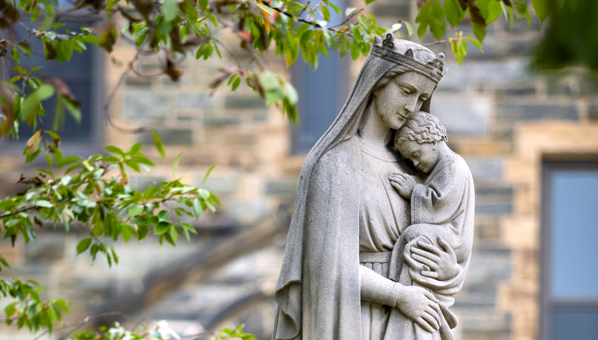 Stone statue on campus of the Virgin Mary holding Jesus 