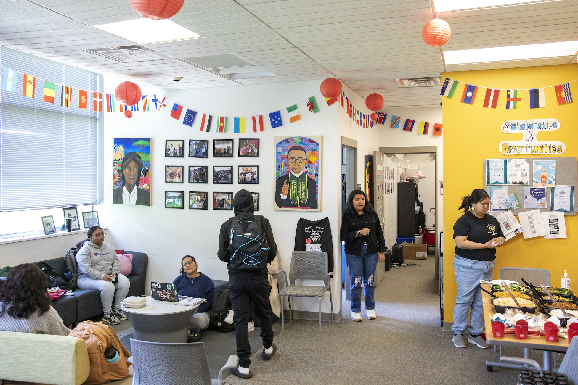 students hang out in the center for cultural engagement office, which has different countries' flags hung around the walls