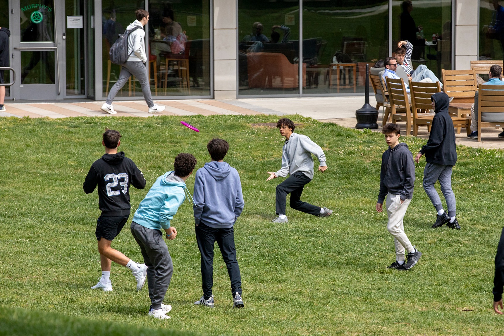 students playing frisbee on a campus lawn