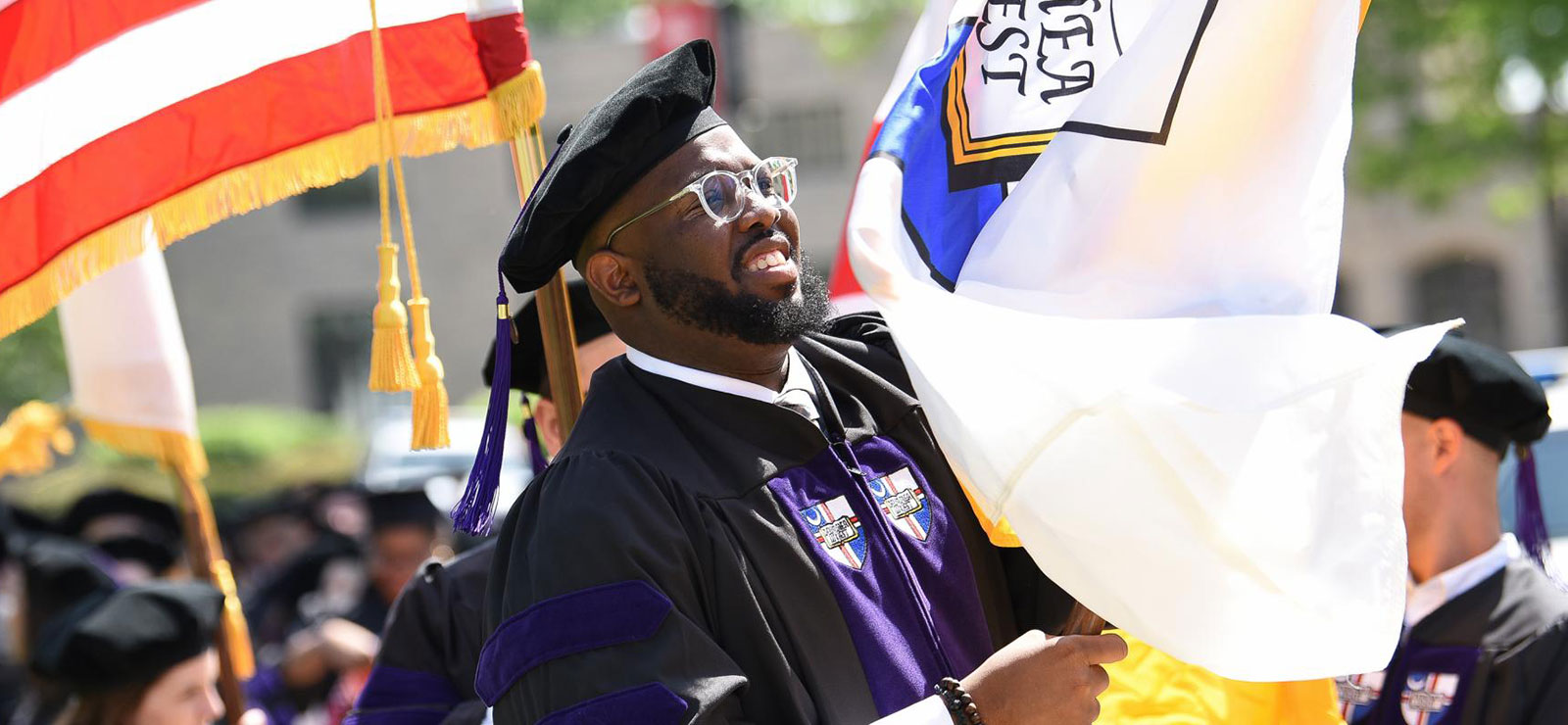 African American student carrying a flag at Commencement.