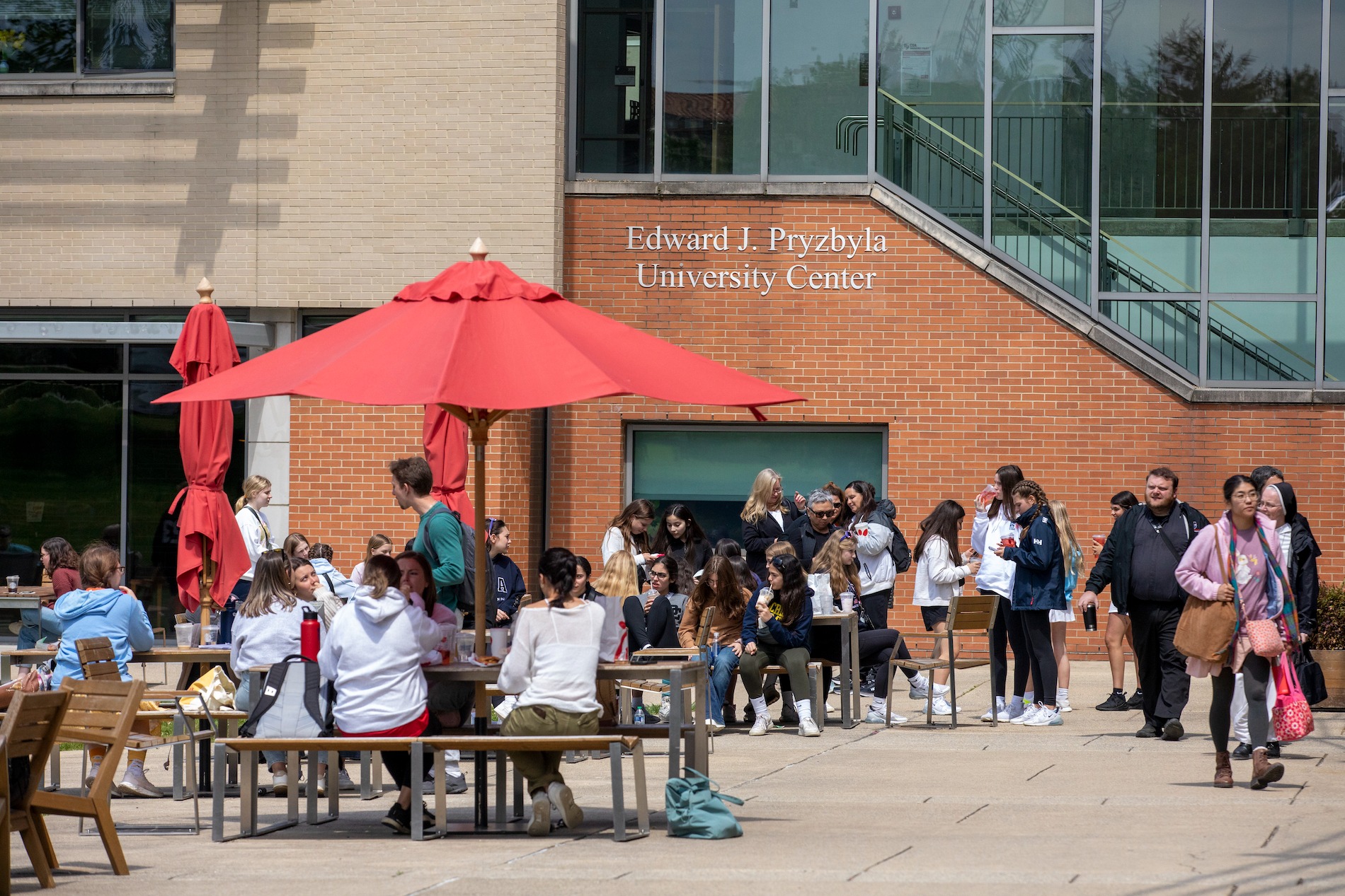 students hanging out at picnic tables in the center of campus