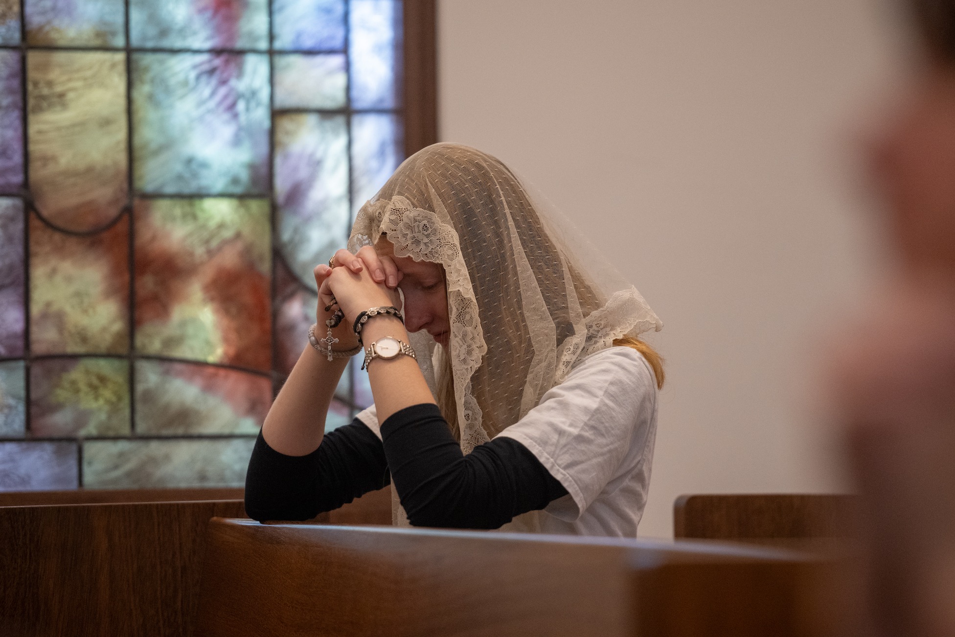 student wearing a veil praying in a chapel