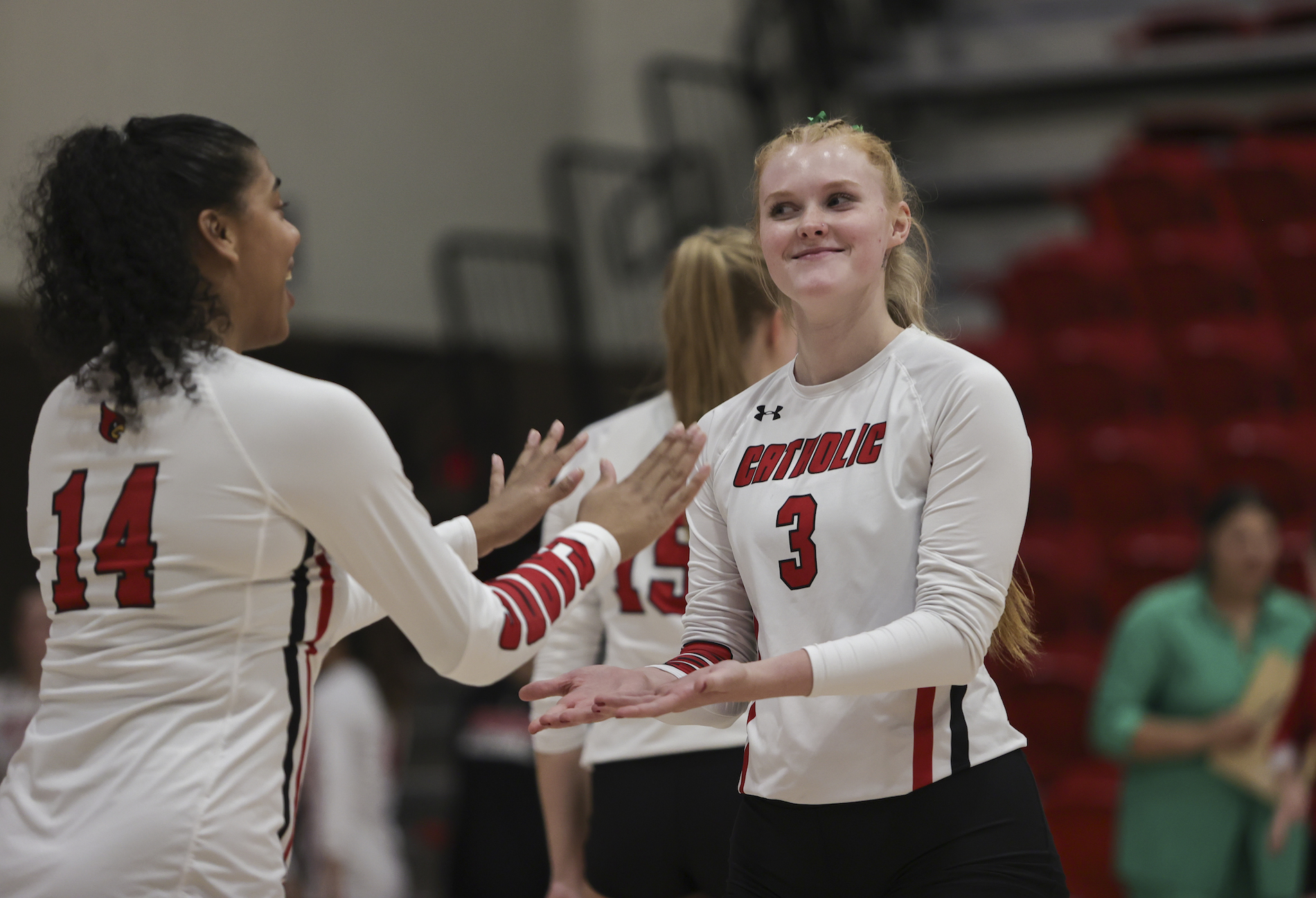 C.U.A. volleyball players high five each other