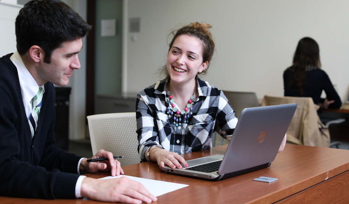 2 adult students on laptops, smiling