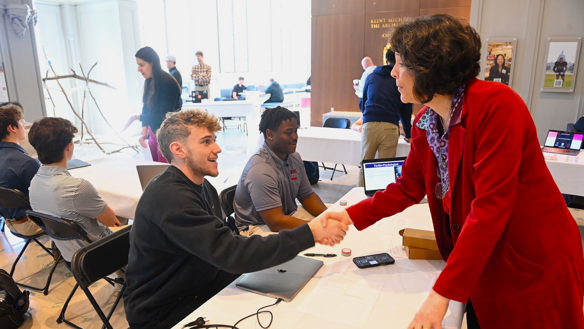 business student shaking professor's hand at a business school trade show for students