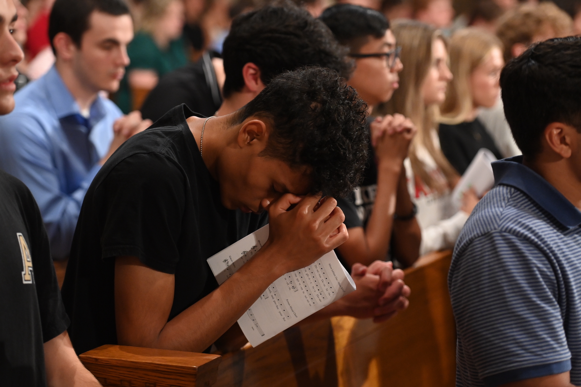 male student in the pews praying