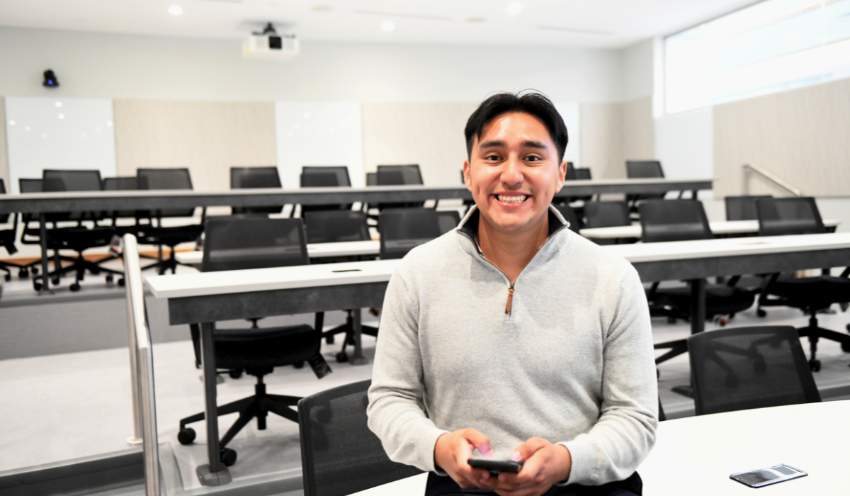 Luis Garcia Abundis is sitting in an empty Catholic University classroom. He is wearing a grey sweatshirt.