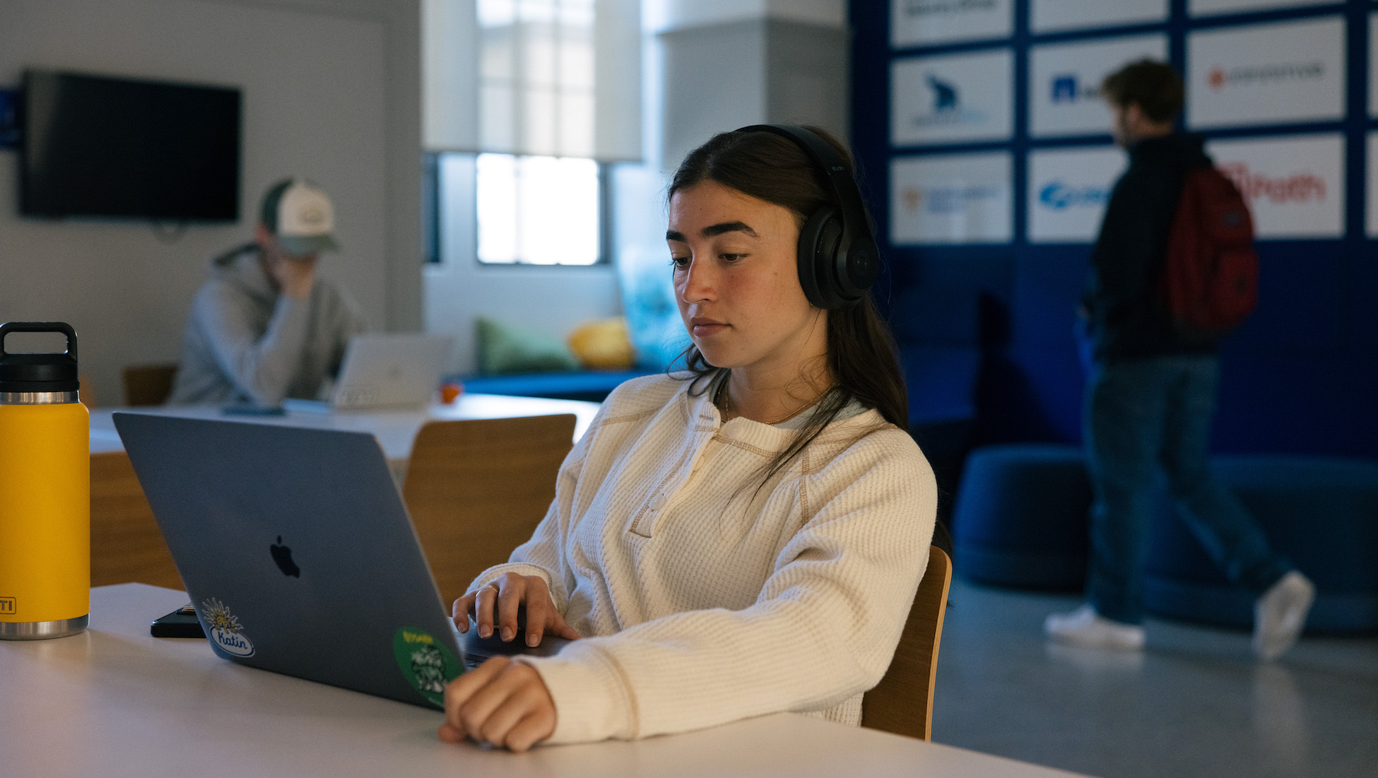 student with headphones on working on her laptop