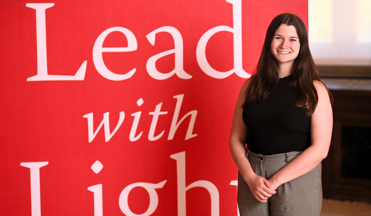 Maria Duffy is standing in front of a red Catholic University background.