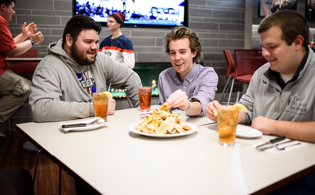 Three CUA students are enjoying drinks and a plate of nachos at Murphy's in the basement of the Pryz.