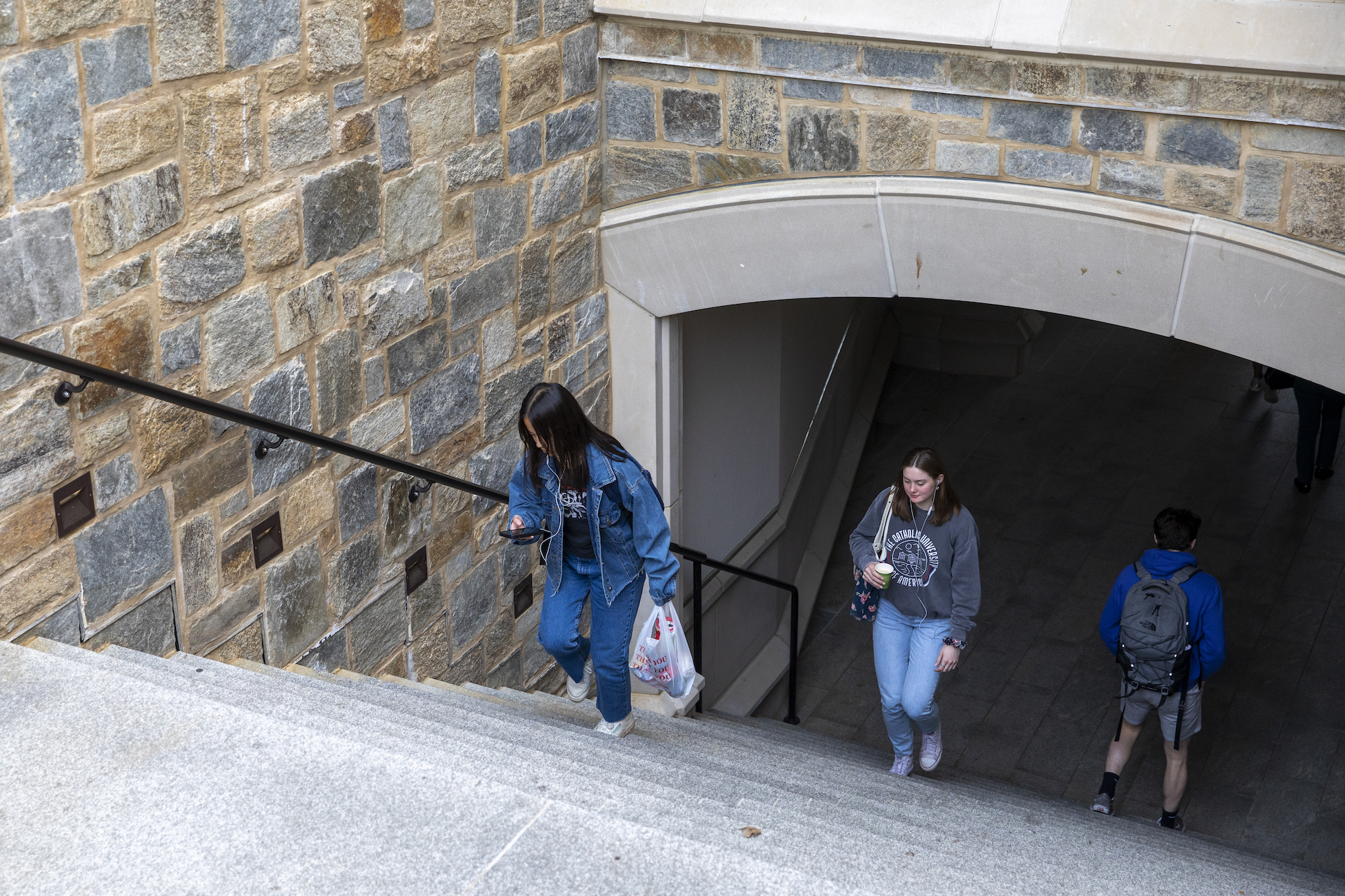 students walking up steps of a campus building