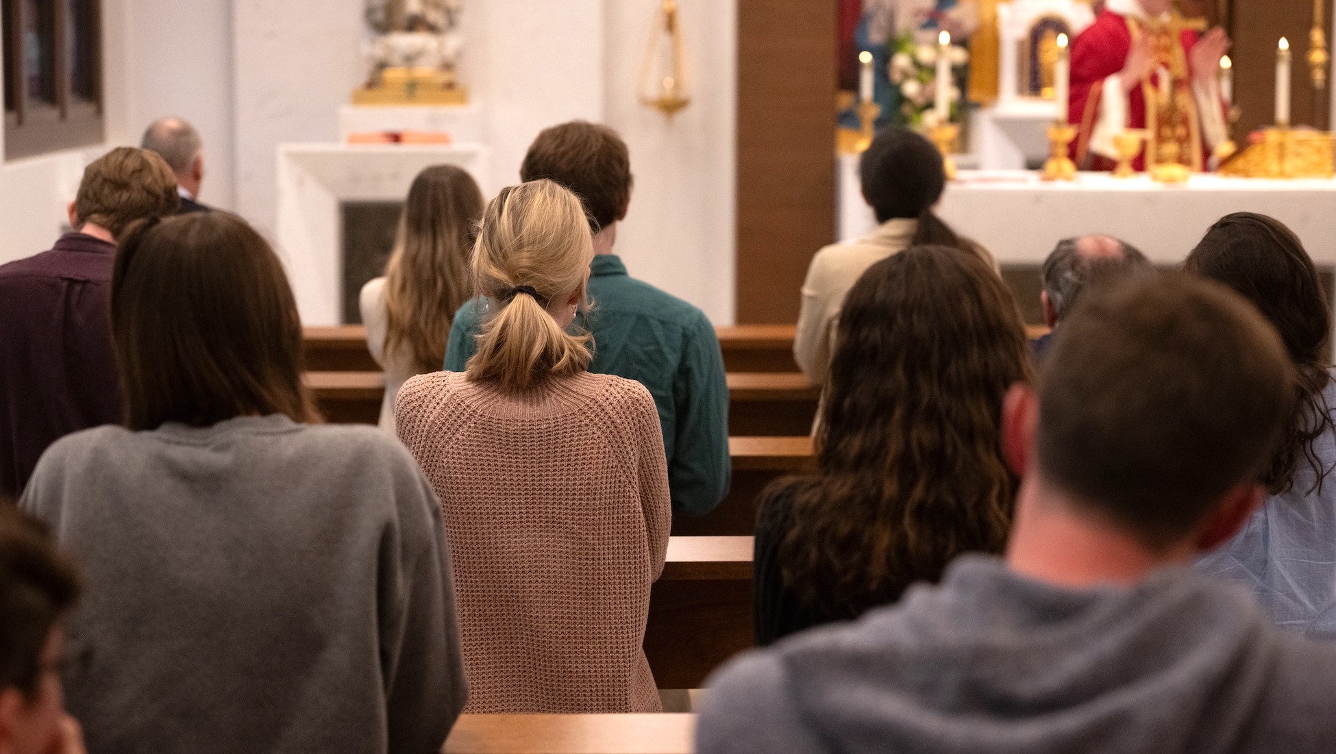 people praying in a chapel during mass on campus