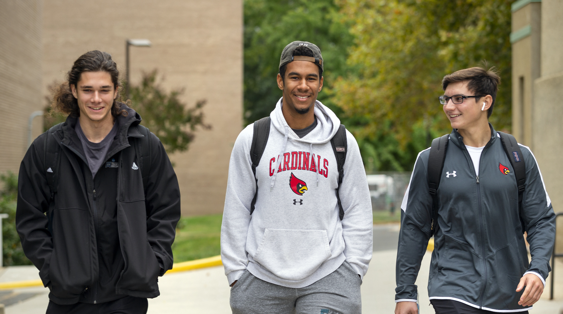 three male students walking and smiling