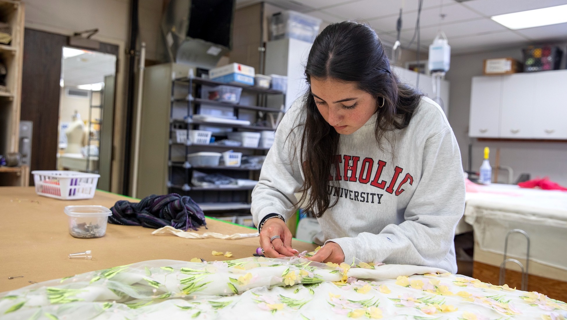 girl sewing a piece of fabric in a room on campus