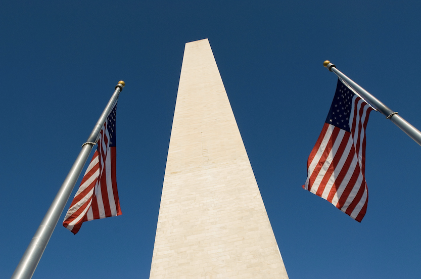 2 US flags on poles in front of the Monument