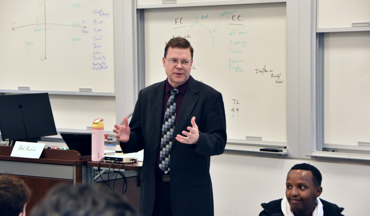 make professor teaching in black suit, wearing glasses