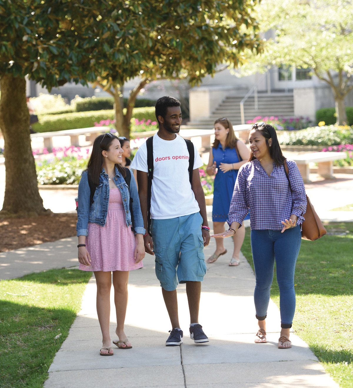 2 girls and a guy walking down campus sidewalk