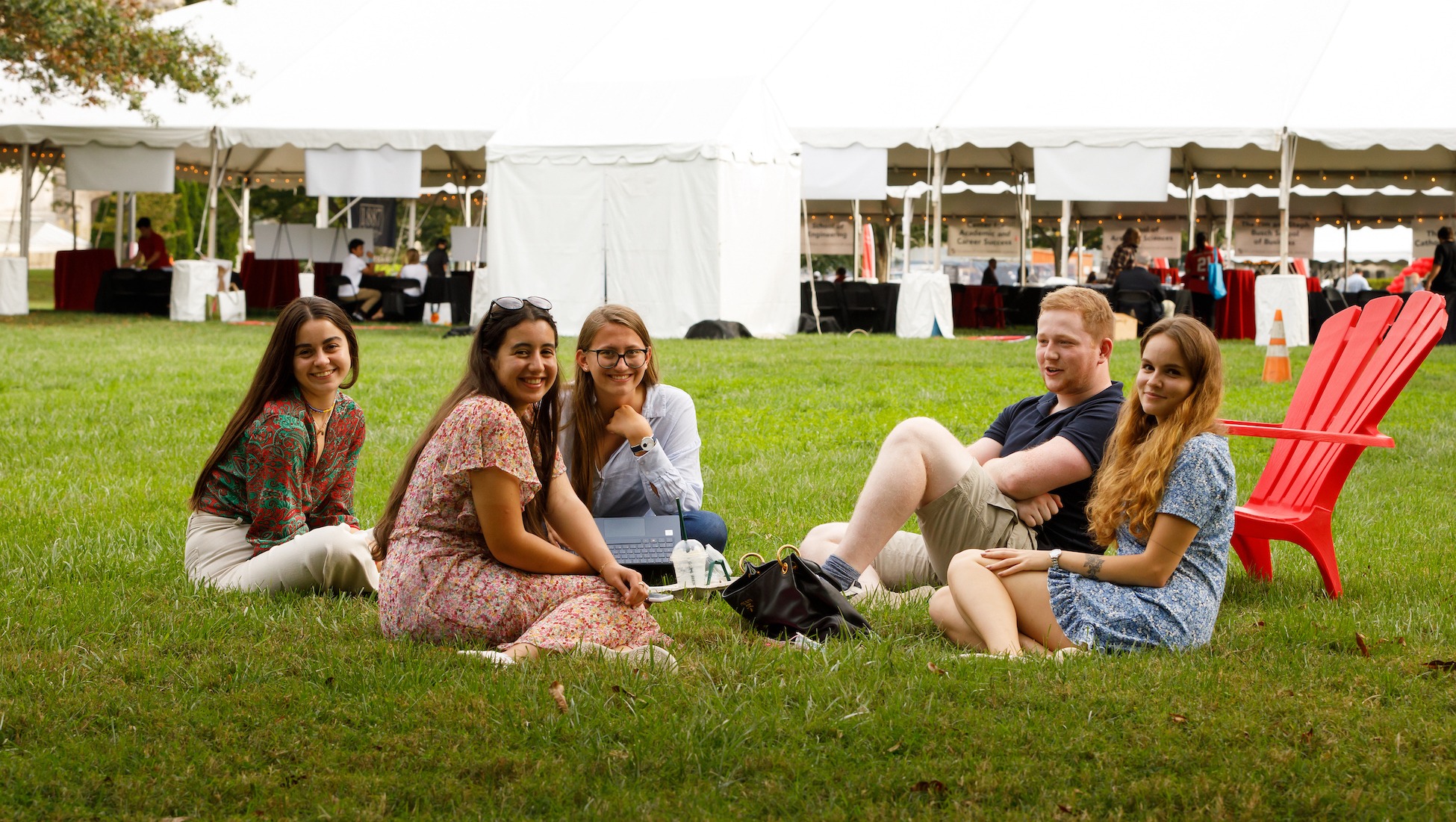 students sitting and chatting on a campus lawn in a circle