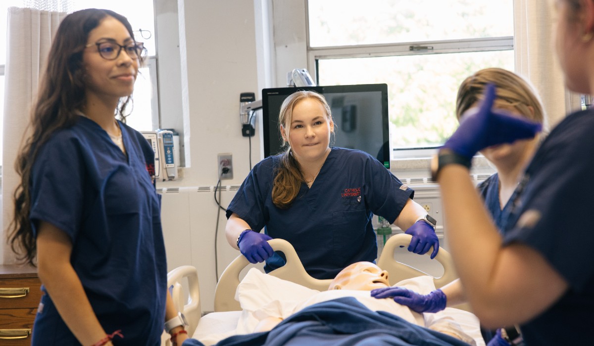 nursing students in scrubs, treating a mannequin patient