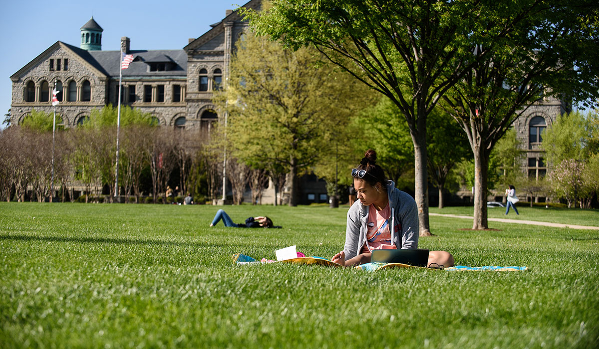 student sitting on grass studying