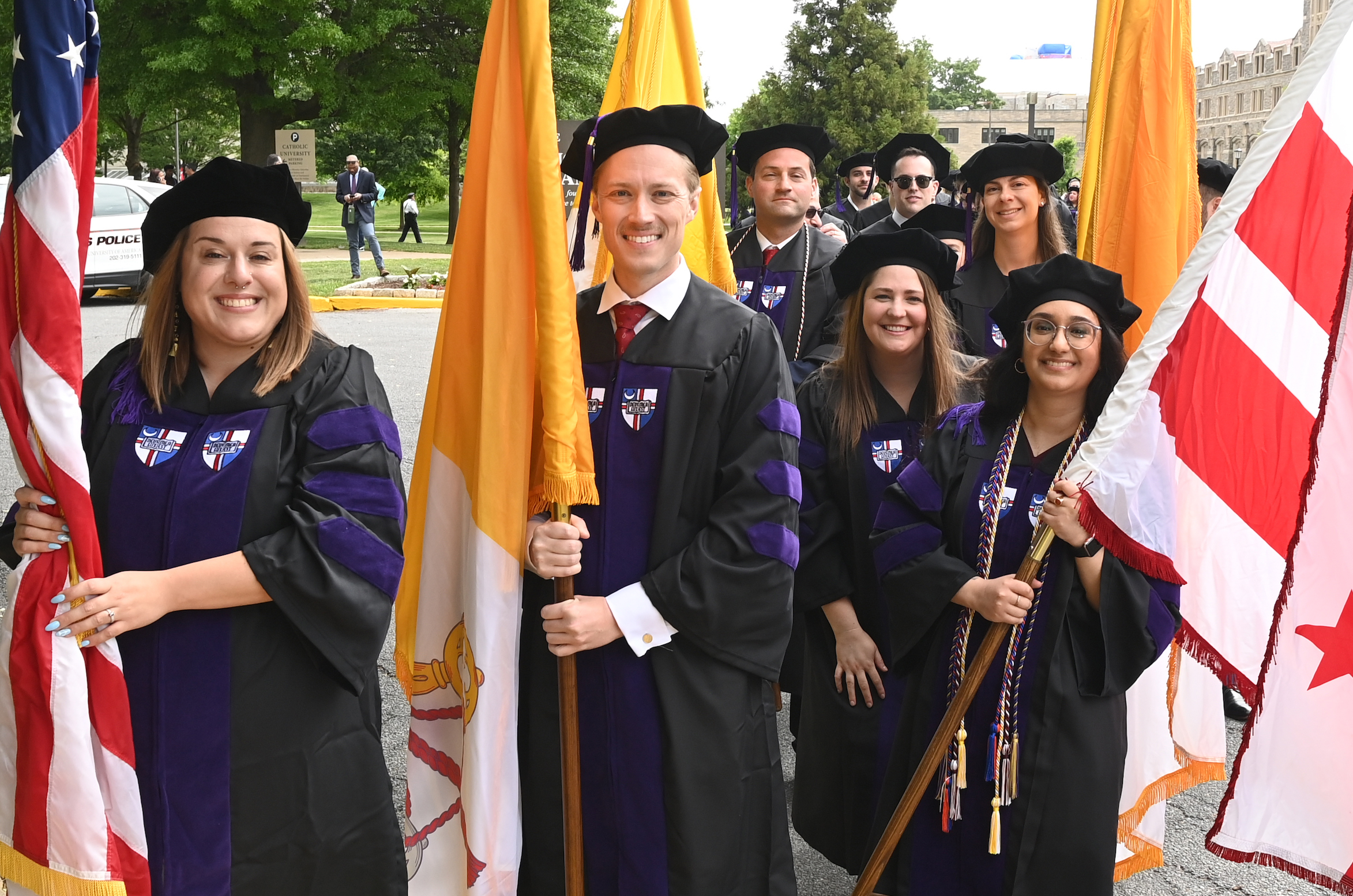 2023 Law School Commencement with Graduates holding flags and smiling