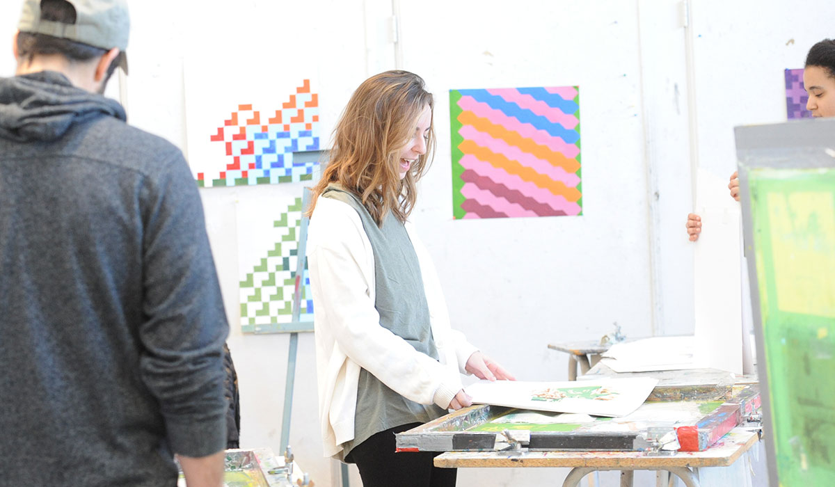 student happily working on an art project in a studio