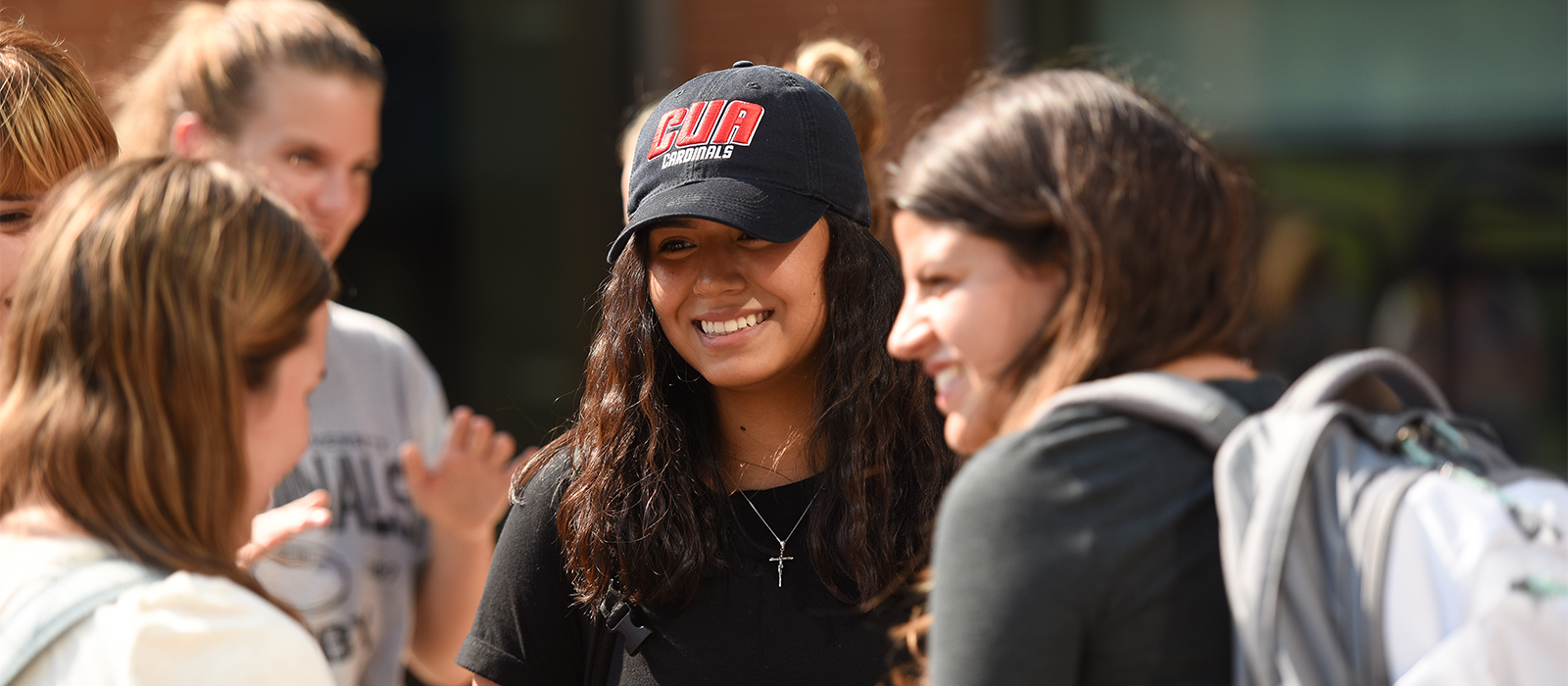 smiling student in a black CUA Cardinals hat