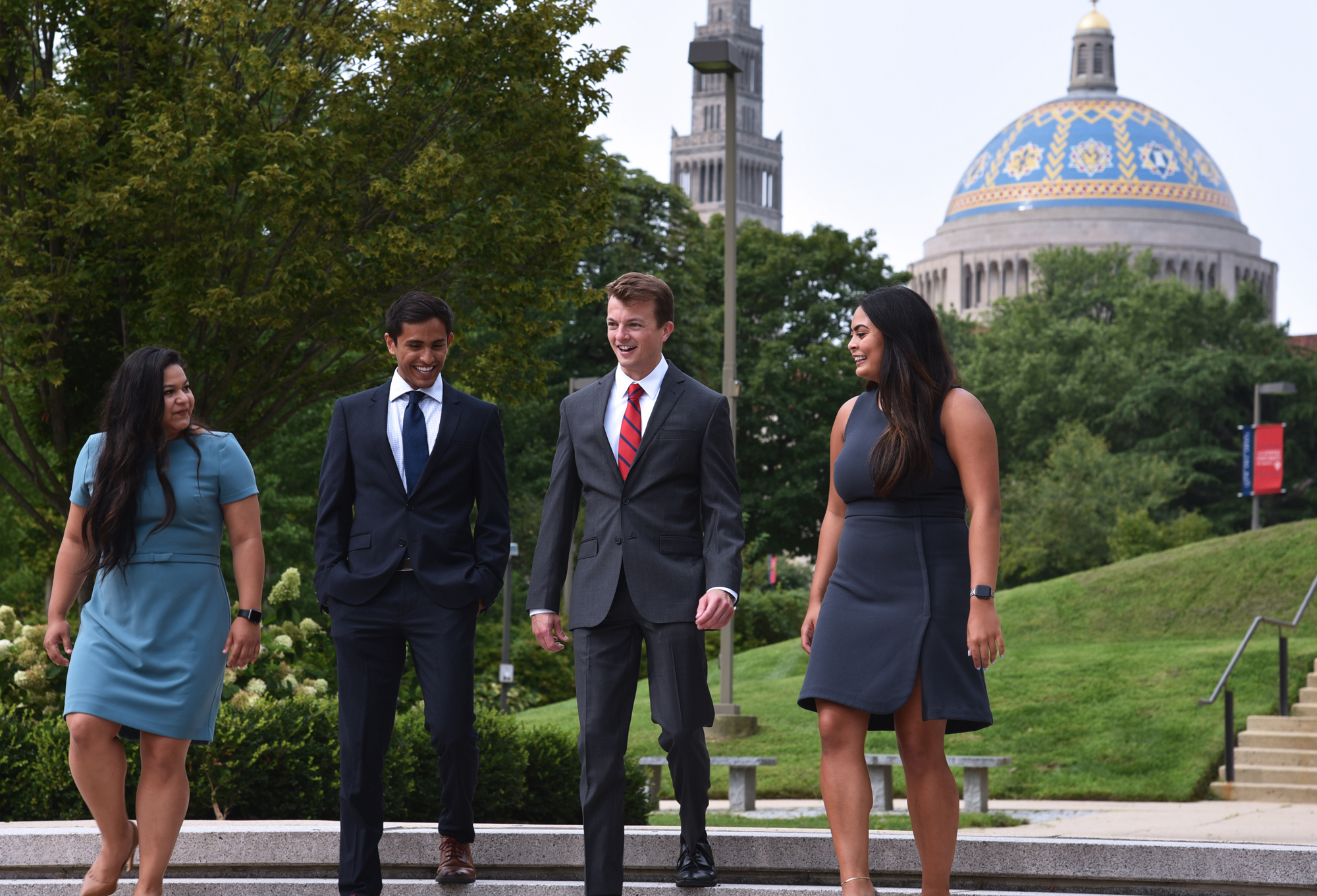 Four students walking in business attire, on campus