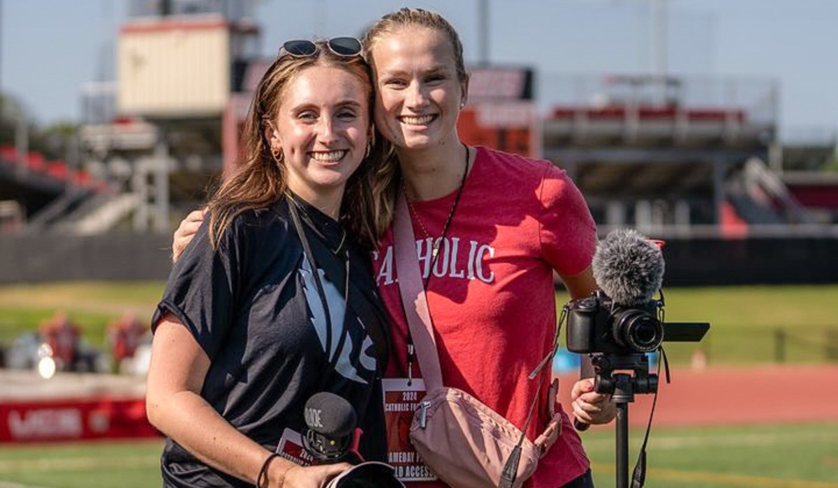 Kathryn Phillips is on the field with a fellow Cardinal, ready to capture content.