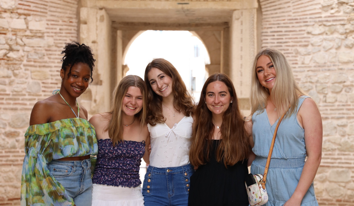 Anisa and four of her friends in front of an ancient wall in Rome.