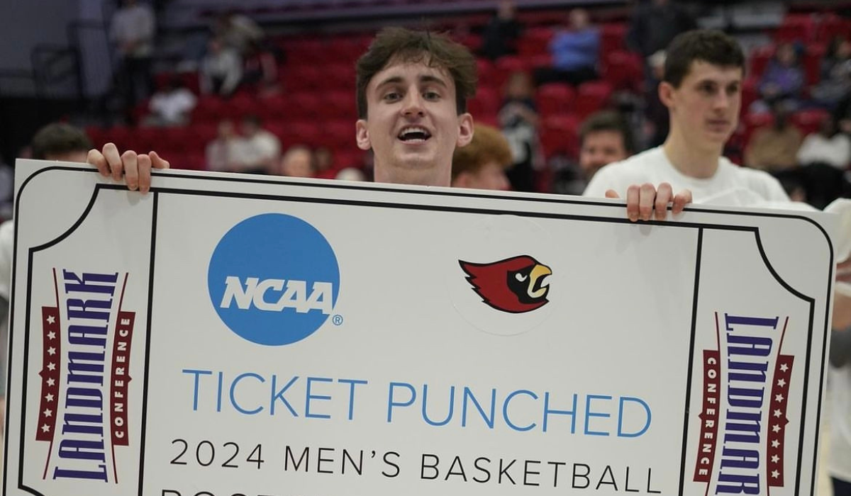 Owen holds a large cardboard sign in the shape of a ticket during a 2024 basketball tournment.