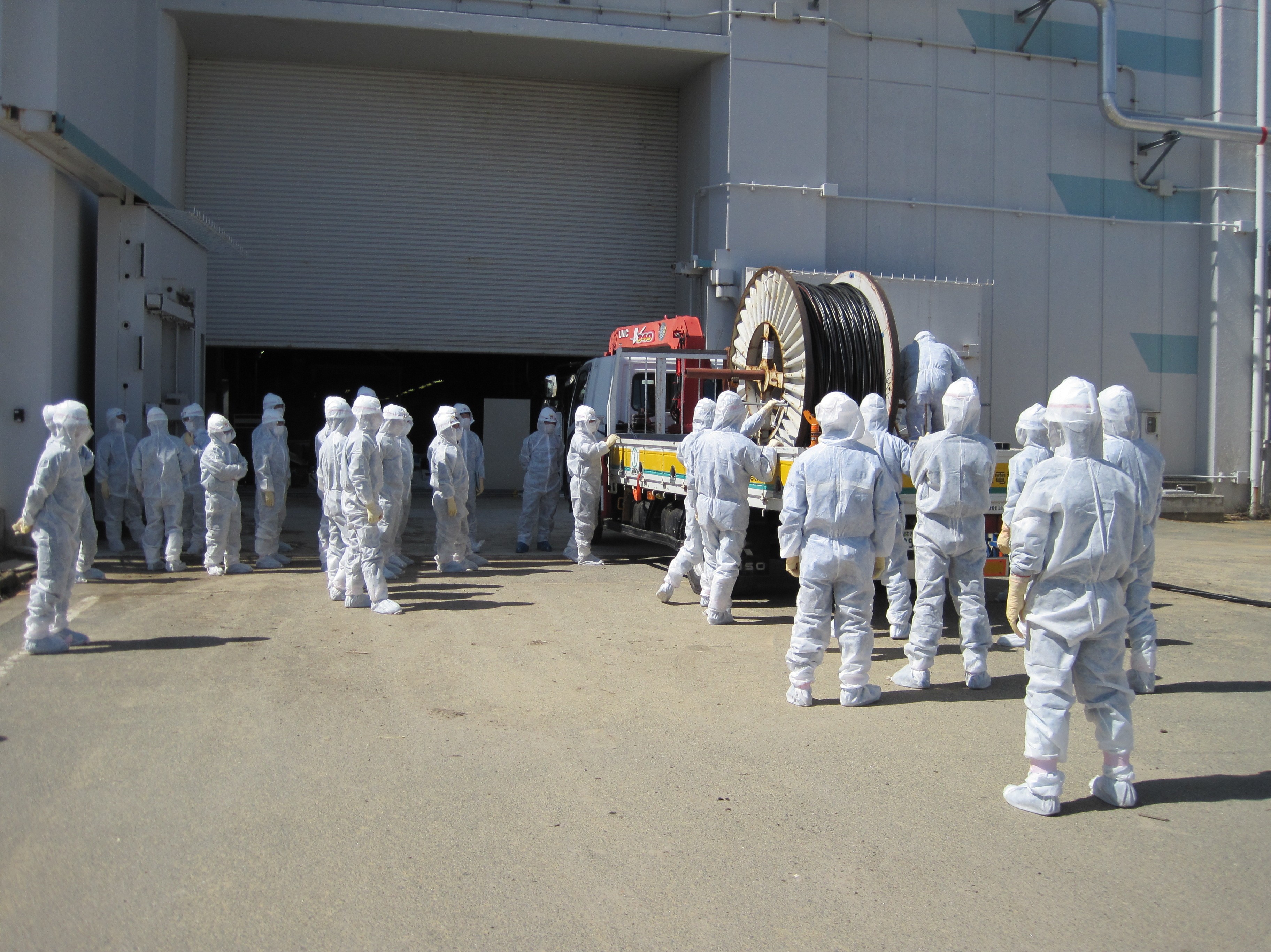 Workers gather in front of massive cable used to manually restore power to reactor cooling systems