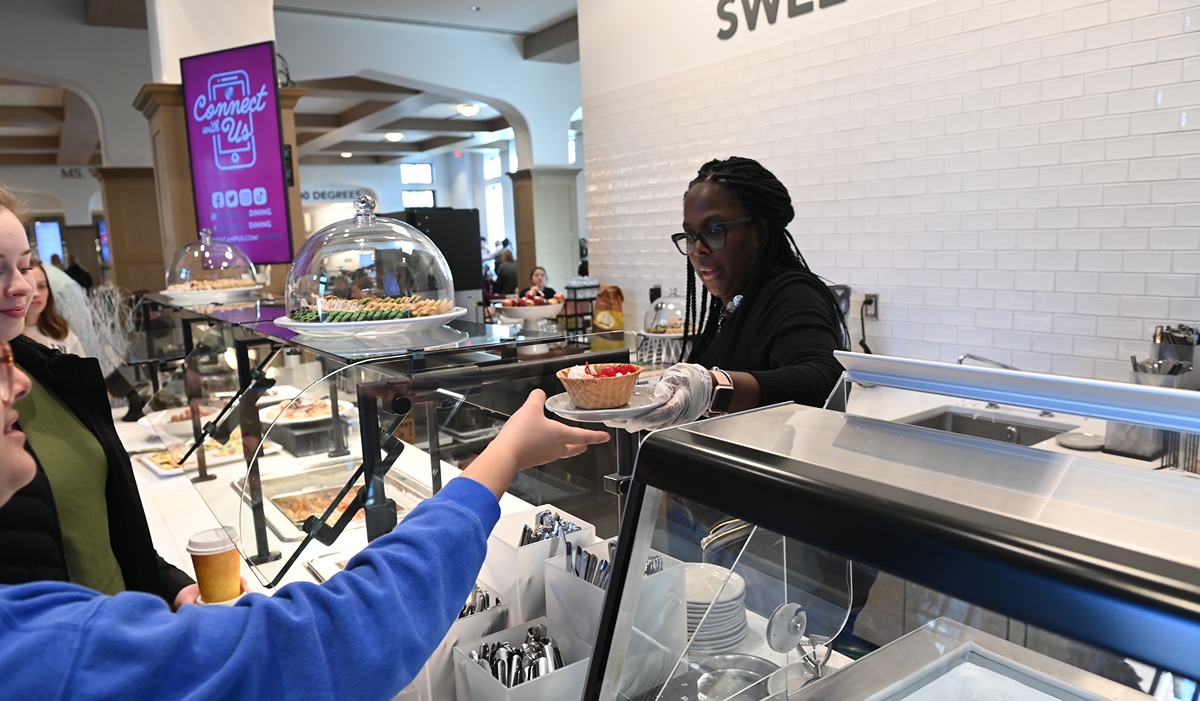 Dining room worker handing someone a desert