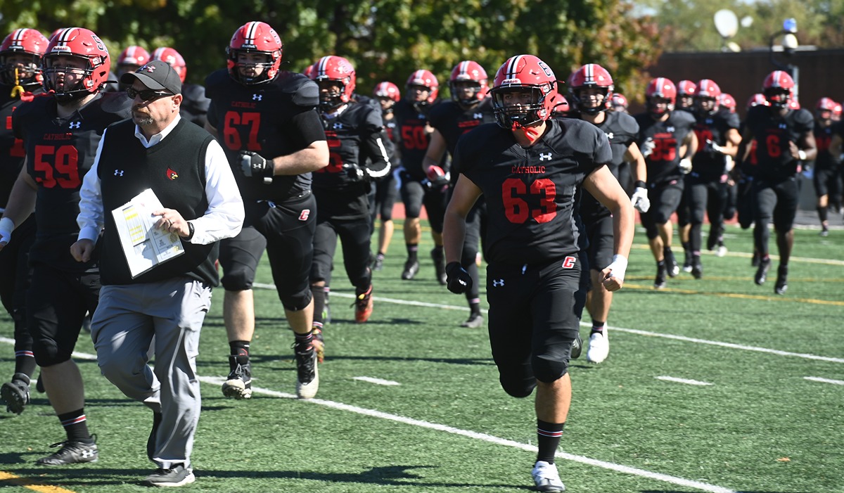 Football players and coach running onto the field