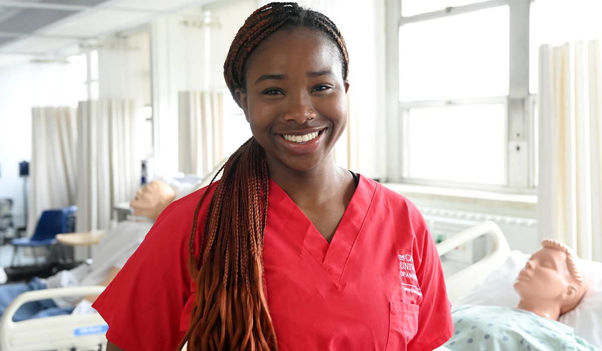 Nursing student imani lipscomb smiling at the camera in red scrubs