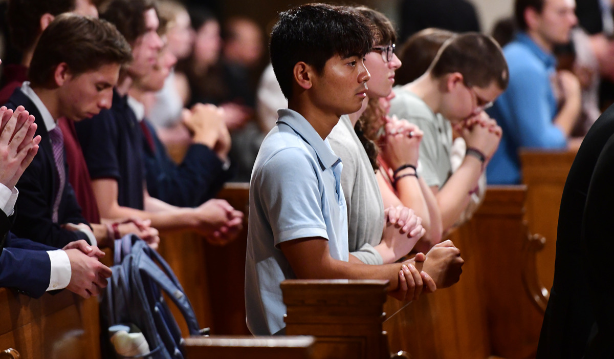 Students praying in a pew