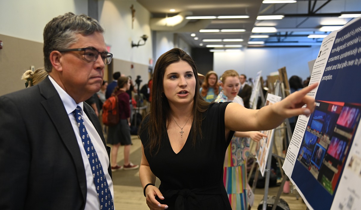 President Kilpatrick viewing a student's research poster while the student explains