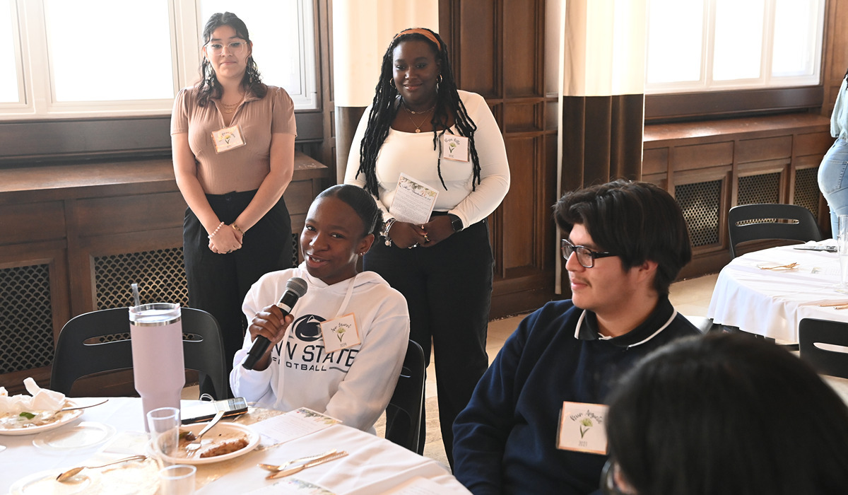 First generation students speaking into a microphone at a table