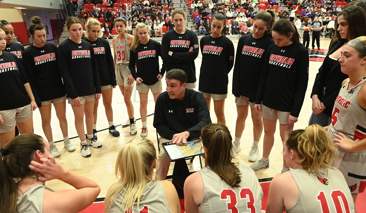 Women's basketball coaching talking to his team in a huddle