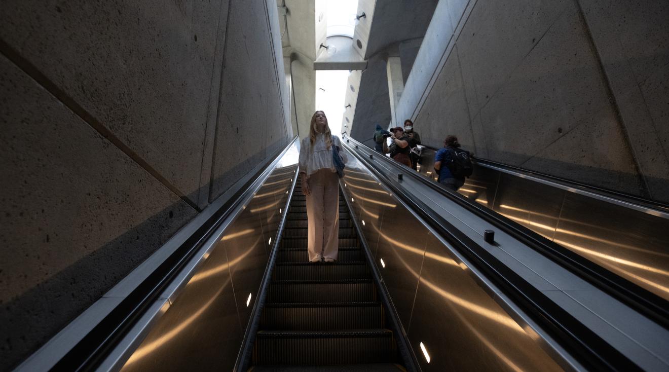 student riding an escalator as she commutes to her internship